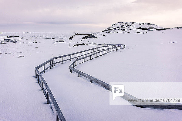 Railings on snow covered land during sunset