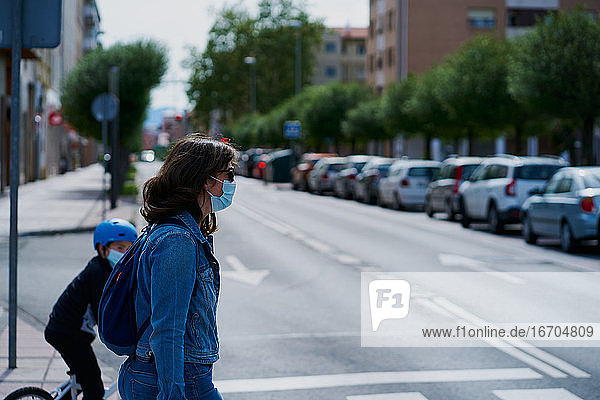 Frau auf der anderen Straßenseite mit einer Maske und Sonnenbrille