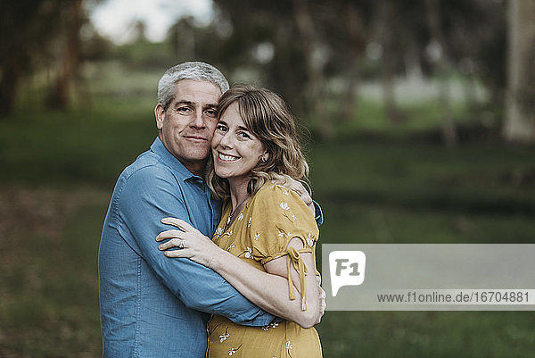 Porträt eines sich eng umarmenden und lächelnden Ehepaars im Wald