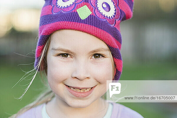 Closeup of a young girl smiling and wearing a colorful hat