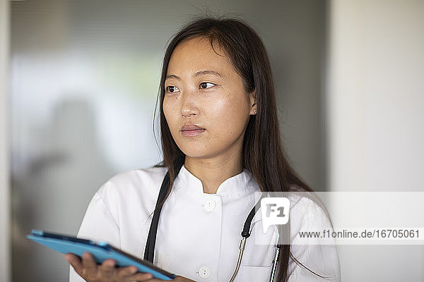 junge Asiatin Ärztin Frau mit Bericht in einer Praxis