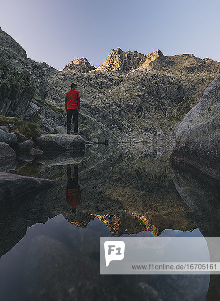 A young man stands on a rock during sunrise at Sierra de Gredos  Spain