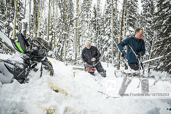 Father and son clearing trails while snowmobiling.