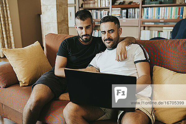 gay couple sitting on the couch looking at the laptop