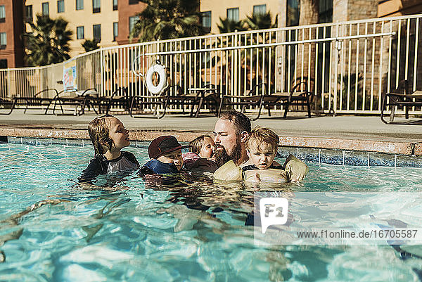 Vater und vier Kinder spielen zusammen im Pool in Palm Springs
