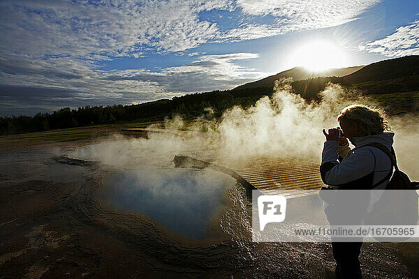 Reife Frau beim Fotografieren eines geothermischen Pools in Island
