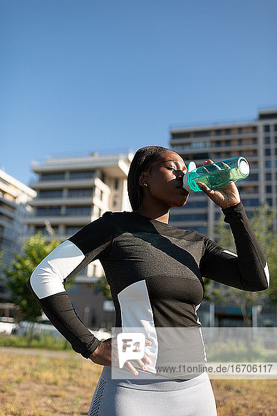 Ethnischer Sportler trinkt in der Pause Wasser
