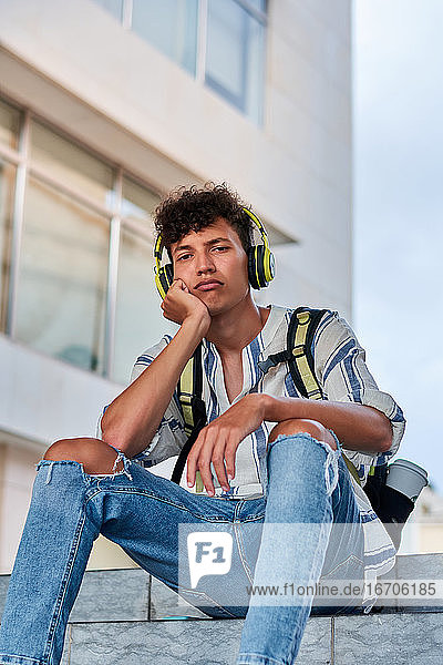 Boring young afro with headphones on sitting on the street