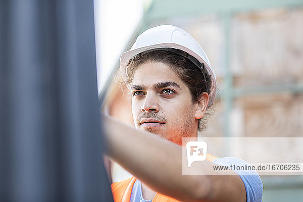 junger Bauingenieur mit Helm bei der Arbeit im Freien