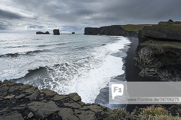 Blick auf den Strand von Kirkjufjara und die Halbinsel Dyrholaey bei bewölktem Himmel  Südisland  Island