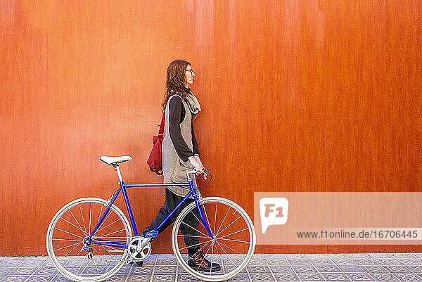 Junge lächelnde Frau auf einer Straße mit Fahrrad