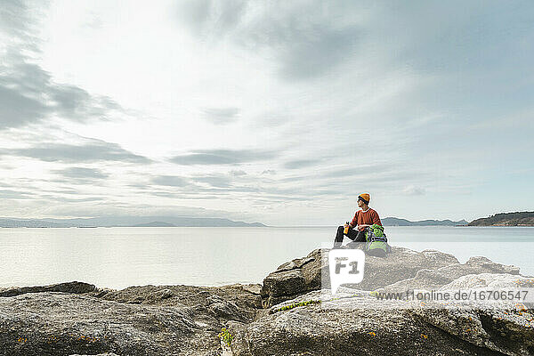 Mann erkundet die Küste auf den Felsen sitzend