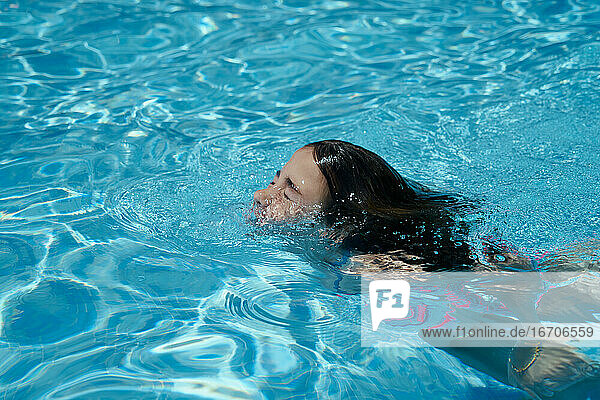 Glückliches lächelndes Mädchen  das schwimmt und Spaß im Schwimmbad hat