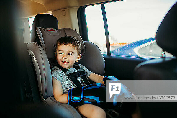 Young boy sitting in car seat wearing boxing gloves