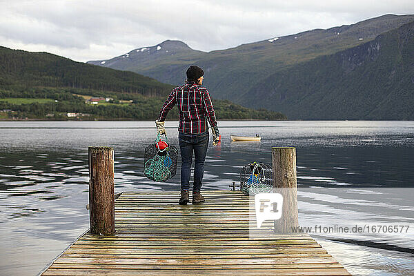 Ein Mann hält einen Krabbenkutter vor einem Dock in Norwegen