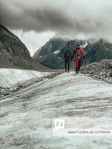 Zwei Bergsteiger beim Abstieg von einem Gletscher in Frankreich unter dramatischen Wolken
