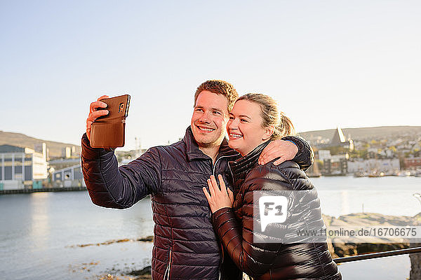 Vergnügtes Touristenpaar macht Selfie an der Strandpromenade