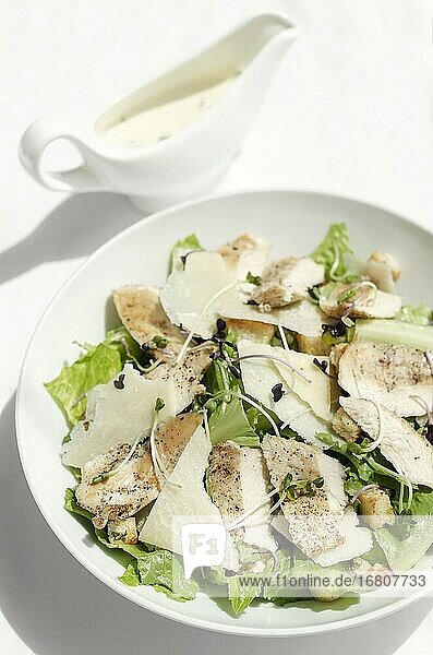 Bio-Huhn-Caesar-Salat mit Parmesan und Croutons auf weißem Tisch Hintergrund.
