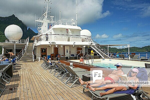 Kreuzfahrtschiff Paul Gauguin  Passagiere entspannen sich auf dem Oberdeck im Schwimmbad. Gesellschaftsinseln  Französisch-Polynesien  Südpazifik.