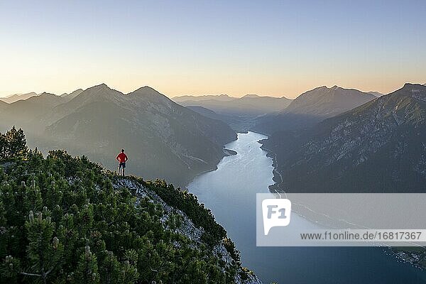 Mountaineer  young man looking over mountain landscape  view from the top of Bärenkopf to Achensee  on the left Seekarspitze and Seebergspitze  sunset in the mountains  Karwendel  Tyrol  Austria  Europe