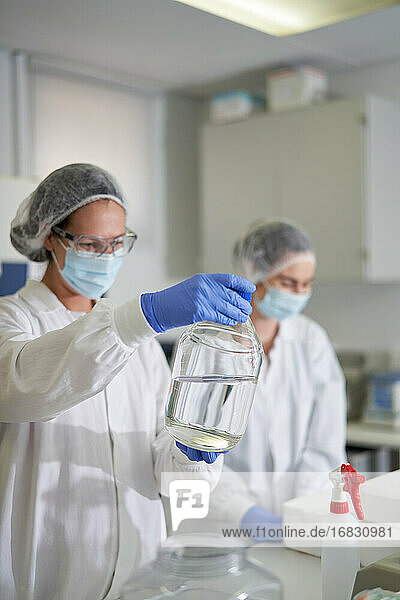 Wissenschaftler in Arbeitsschutzkleidung bei der Untersuchung einer Flüssigkeit im Labor