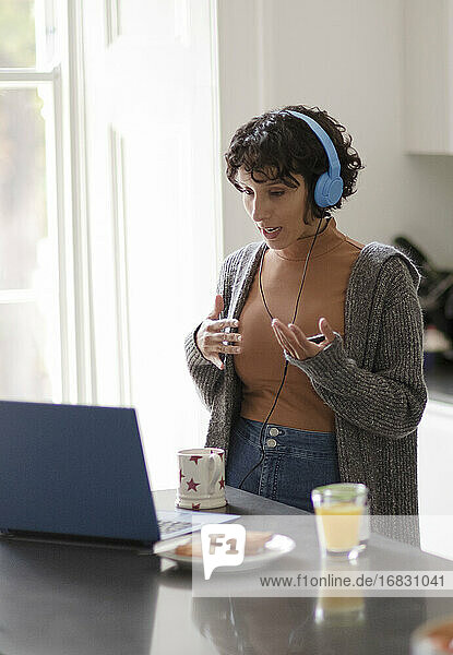 Frau mit Kopfhörer auf Videoanruf arbeiten von zu Hause aus am Laptop