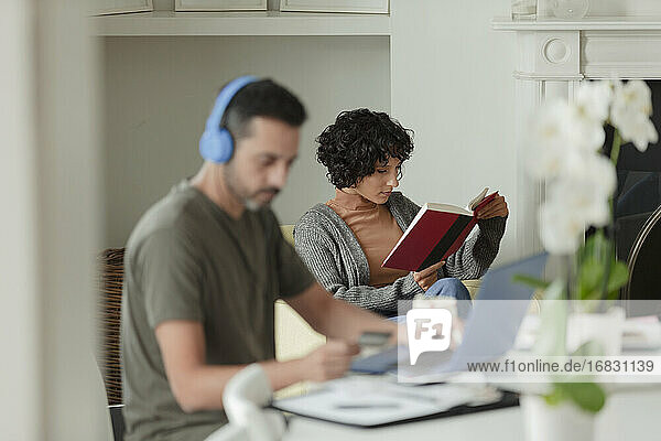 Ehepaar liest und arbeitet von zu Hause aus am Laptop