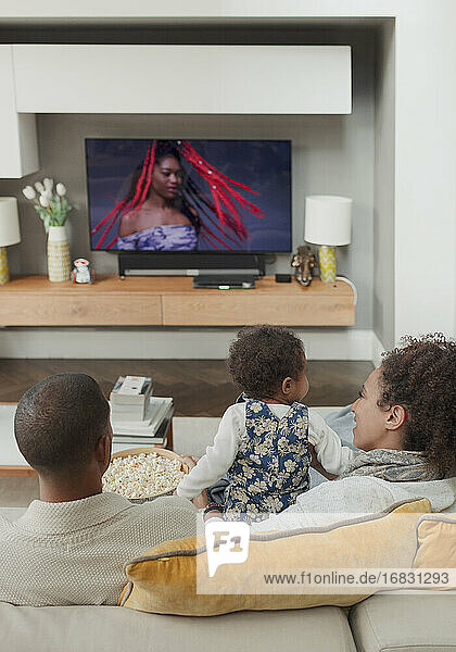 Familie beim Fernsehen auf dem Wohnzimmersofa