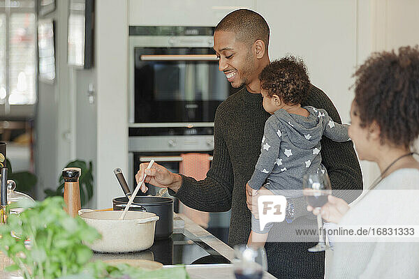 Glückliches Paar mit Baby Tochter Kochen Abendessen in der Küche