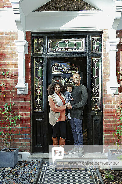 Porträt glückliches Paar mit Baby Tochter an sonnigen Haus Haustür
