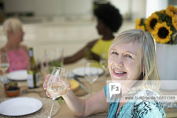 Porträt glücklich ältere Frau trinken Weißwein mit Freunden am Tisch