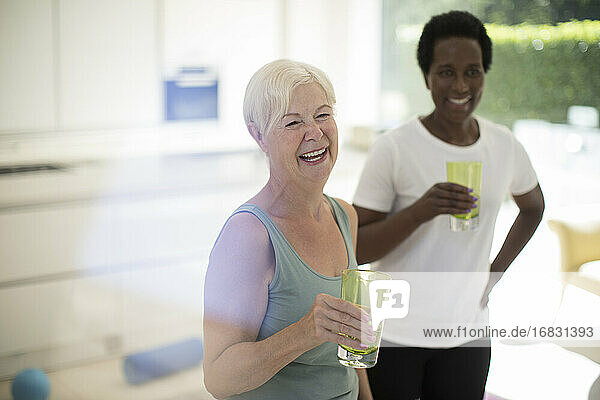 Happy senior women friends drinking water after workout at home