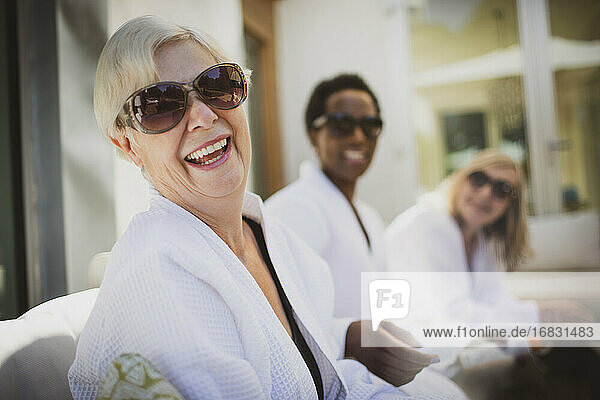 Portrait happy senior woman in spa bathrobe laughing on patio