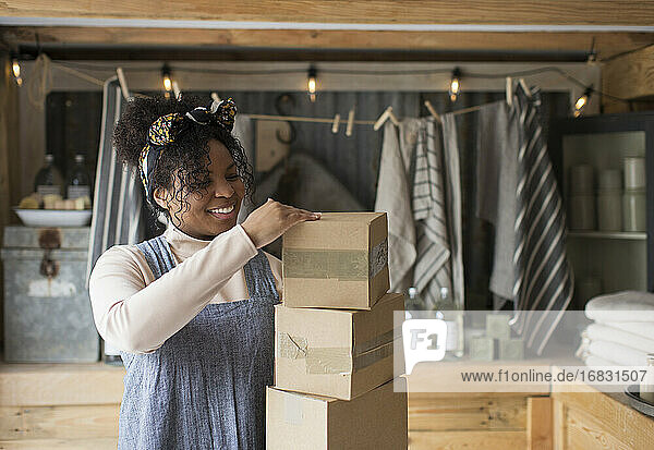 Lächelnde Ladenbesitzerin mit Stapel von Kartons