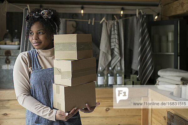 Porträt zuversichtlich weiblichen Ladenbesitzer mit Stapel von Kartons