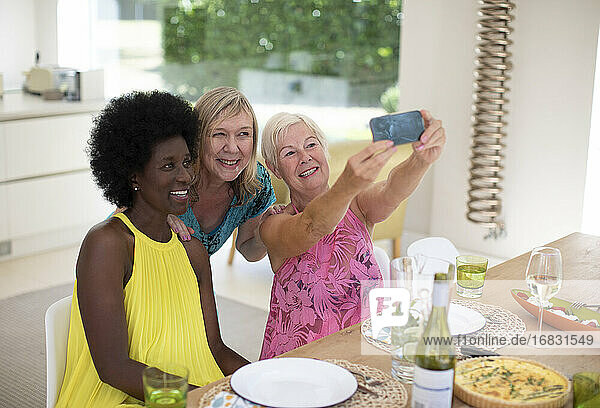 Happy senior women friends taking selfie at luncheon