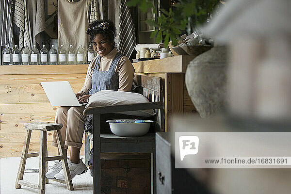 Porträt glückliche weibliche Ladenbesitzerin mit Laptop in Haushaltswarengeschäft