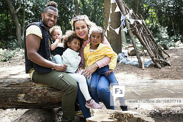 Porträt glückliche liebevolle Familie auf gefallenen Stamm im Wald