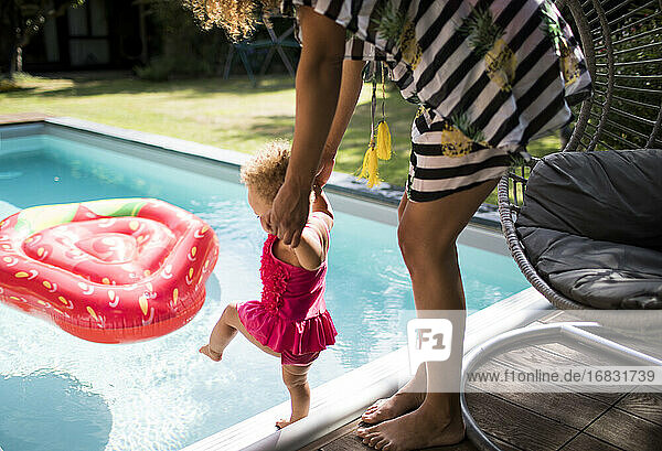 Mutter hilft Kleinkind Tochter im Sommer Schwimmbad