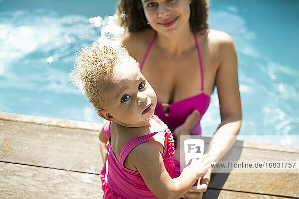 Porträt niedlichen Kleinkind Tochter mit Mutter am sonnigen Schwimmbad Rand