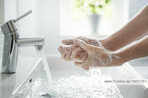 Close up Teenager Junge waschen Hände mit Seife und Wasser am Waschbecken