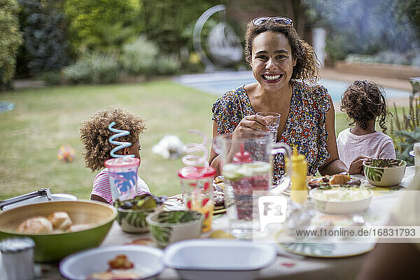 Portrait happy mother enjoying summer barbecue with family on patio
