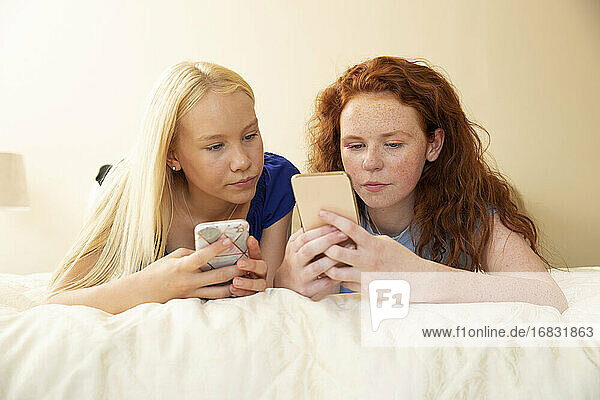 Preteen Mädchen Freunde mit Smartphones auf dem Bett
