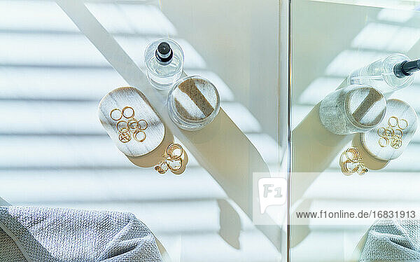 Blick von oben goldene Ohrringe auf sonnigen Badezimmertisch
