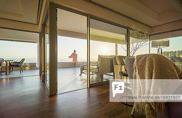 Frau genießt sonnigen Ozean Sonnenuntergang Blick von Luxus-Terrasse