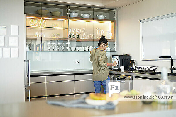 Woman preparing espresso at machine in modern home showcase kitchen