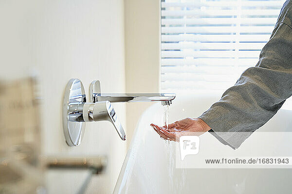 Frau  die die Wassertemperatur aus dem Wasserhahn der Badewanne im Badezimmer überprüft