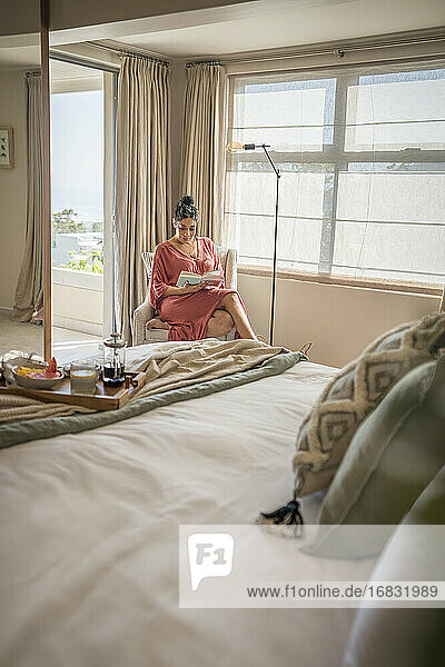 Frau entspannt mit Buch im Schlafzimmer am Morgen
