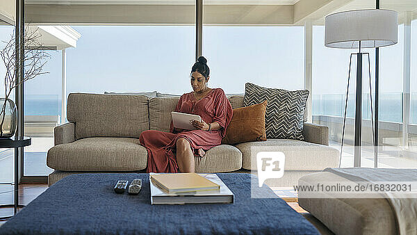 Frau entspannt sich mit digitalem Tablet auf luxuriösem Home-Showcase-Sofa
