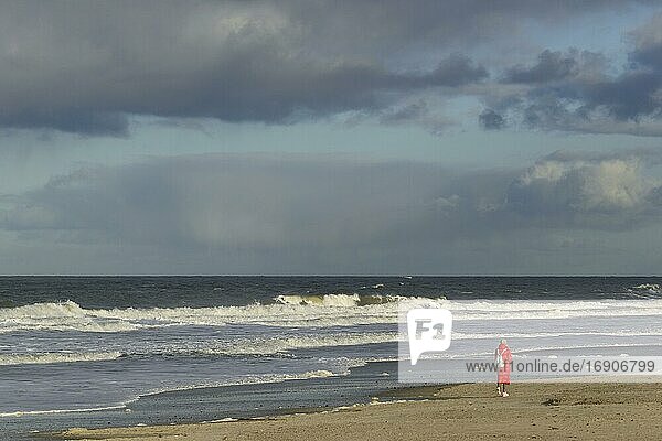 Wellen am Sandstrand  einzelne Person am Spülsaum beim Spazierengehen  Nordsee  Norderney  Ostfriesische Inseln  Niedersachsen  Deutschland  Europa